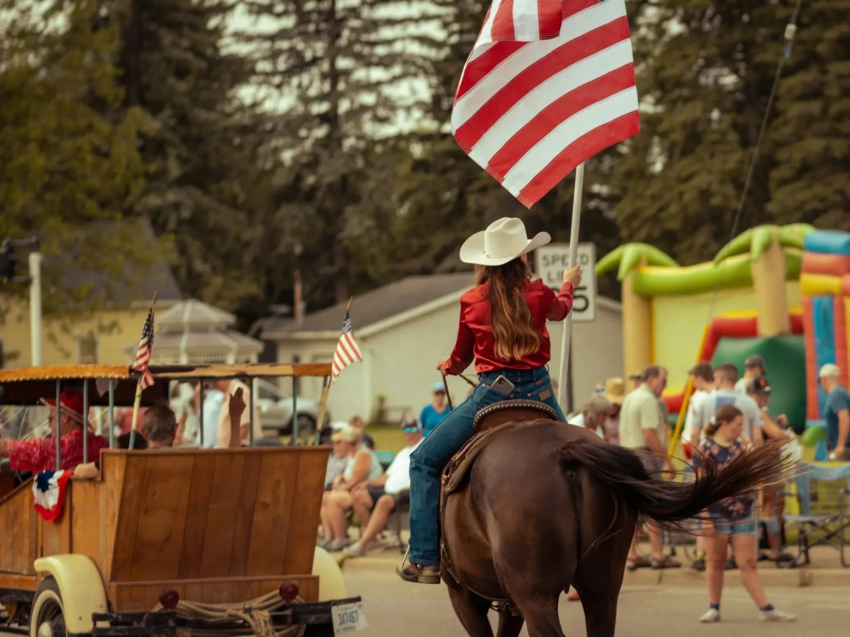 A woman riding a horse in a parade carrying the American Flag